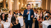 Animateur de mariage au micro entre les tables d'une salle de réception, les invités rient