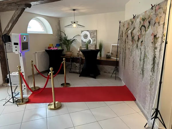 Installation photobooth mariage Le Cadre Magique avec mur de fleurs et tapis rouge